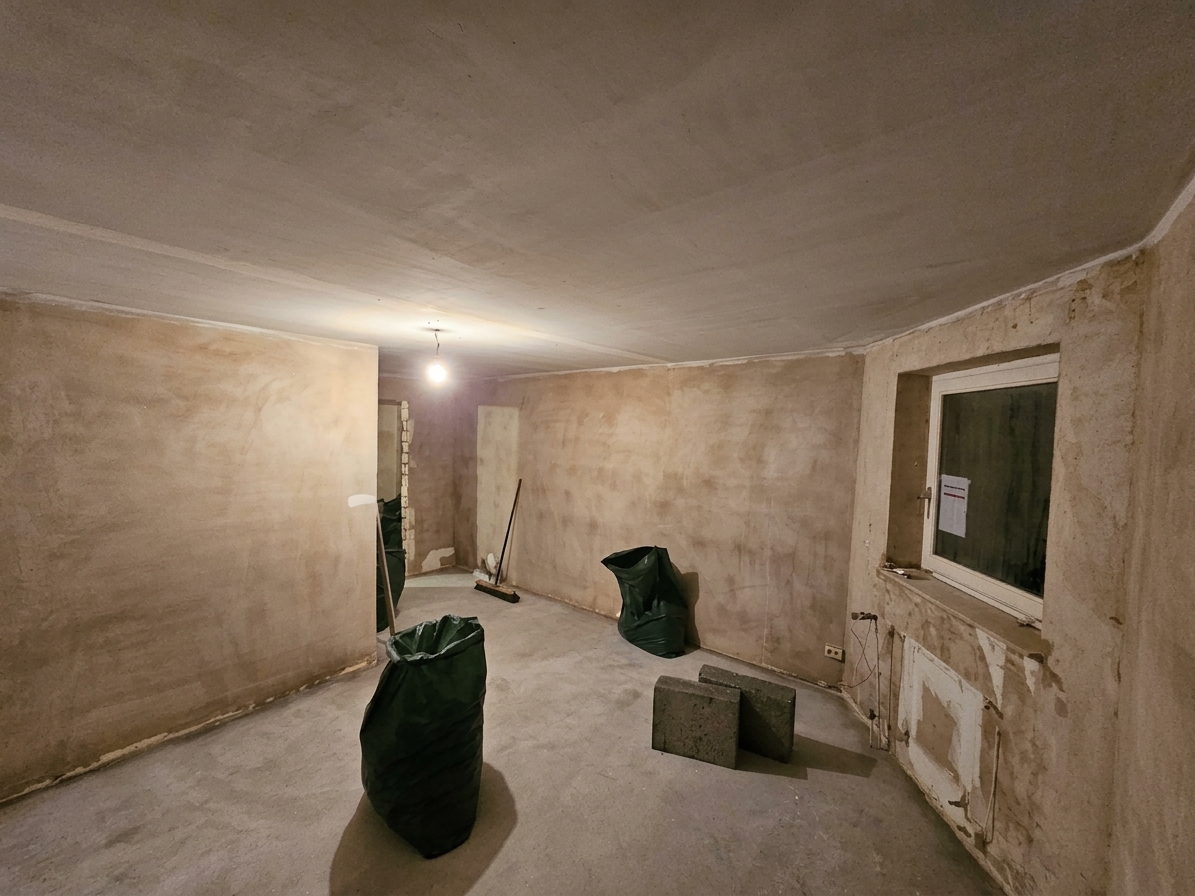 Rohbauzustand: Wände und Decke neu verputzt, der alte Heizkörper demontiert, der Boden für den Neuaufbau vorbereitet.